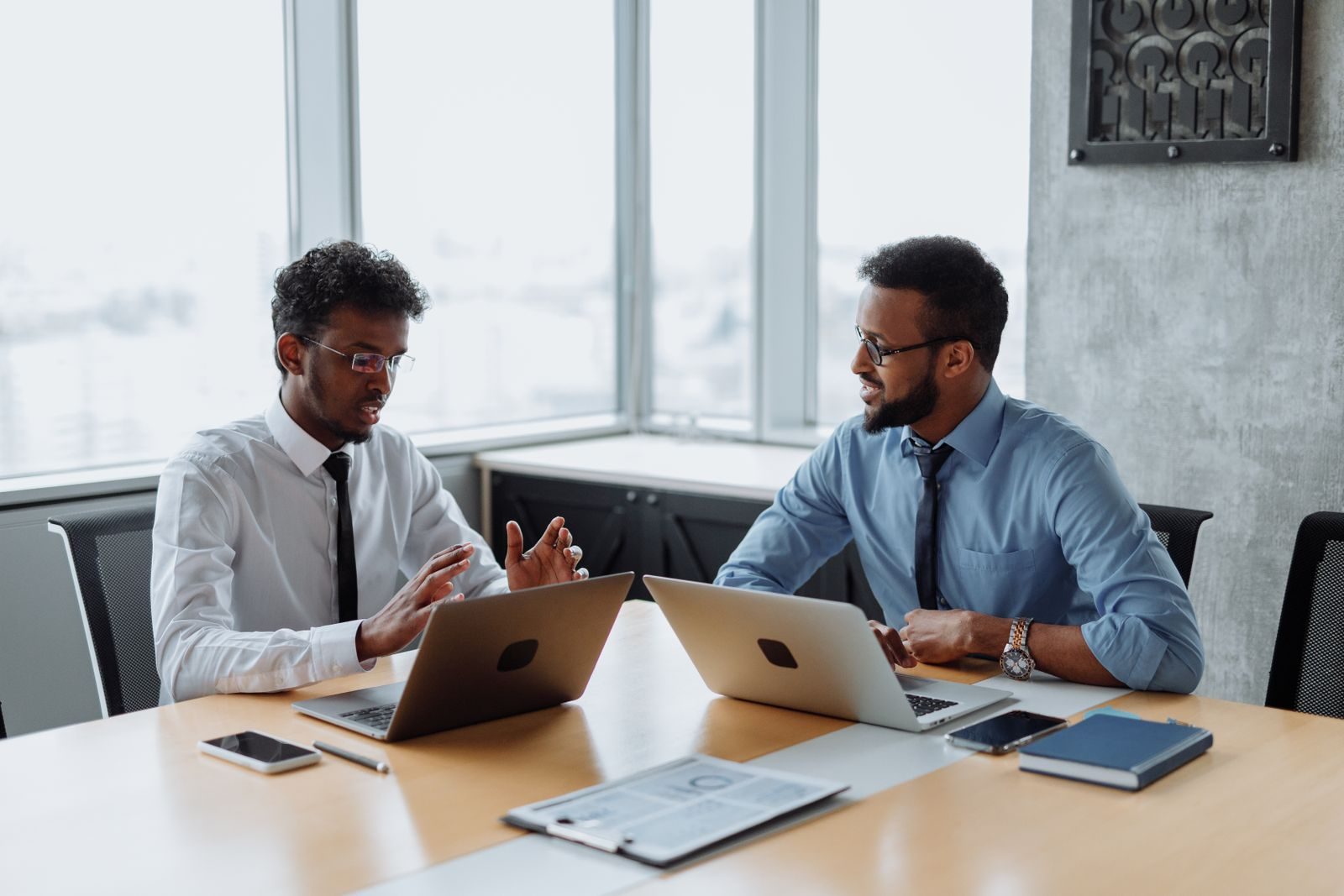 Two professionals discussing strategy over laptops